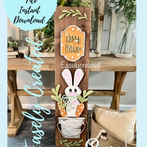 May include: A wooden sign featuring a bunny holding carrots in a bucket. The sign reads "Hoppy Easter" and is adorned with green leaves and white polka dots.