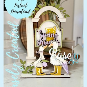 May include: A wooden spring-themed sign with two ducks wearing yellow rain boots. The sign reads "Spring Showers".