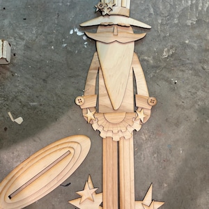 May include: Wooden cutout of a patriotic Uncle Sam figure with a tall hat, stars, and a beard. The figure is holding a banner with stars and is standing on a base with stars. The figure is made of unfinished wood.
