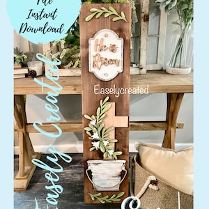 May include: A wooden sign with a brown background and a white sign that says "He is Risen" with green leaves and a cross. The sign is decorated with a white bucket and green leaves. The sign is labeled "Easlycreated".