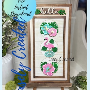 May include: A wooden sign with a brown frame and a white background. The sign has three round cutouts with a pink flamingo, a pink hibiscus flower, and a blue hibiscus flower. The sign also has the text "hello" and "EaslyCreated".