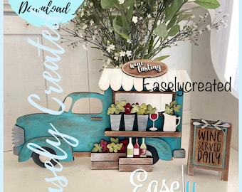 May include: A teal blue vintage truck with a white awning and a sign that says "Wine Tasting". The truck is decorated with flowers, grapes, and wine bottles. There is a sign that says "Wine Served Daily" next to the truck.