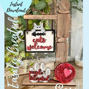 May include: A wooden cat-themed sign with the text "cats welcome" and "people tolerated." The sign features a cat, fish bones, a paw print, and a red yarn ball with a heart. The words "Digital Cut File Instant Download" are also visible.