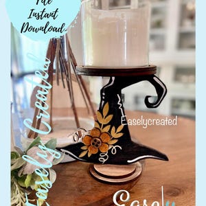May include: A black witch hat candle holder with a gold flower design. The candle holder is made of wood and has a clear glass candle holder on top. The text "Easlycreated" is visible on the side of the candle holder.