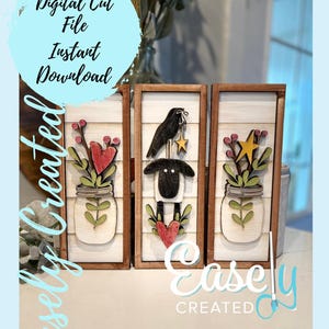 Op de afbeelding: Drie houten borden met een boerderijthema. De borden tonen een zwarte vogel, een wit schaap en een glazen pot met bloemen. De borden zijn allemaal omlijst met hout en hebben een witte achtergrond.