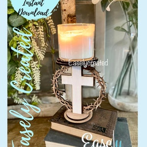 May include: A wooden cross with a thorn crown around it, holding a candle in a glass jar. The cross is on a stack of books with the text "Easly Created" on the bottom book.