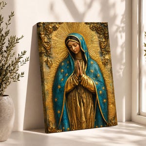 May include: A rectangular wall art piece featuring a relief-style depiction of the Virgin of Guadalupe. The figure wears a gold gown and a teal mantle adorned with gold stars, with hands clasped in prayer against a textured gold sunburst background.