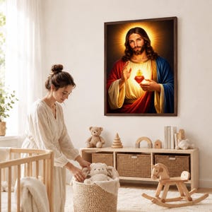 Sacred Heart of Jesus framed painting in a dark wood frame hanging in a nursery. A mother stands near a wooden crib, organizing a plush rabbit toy in a woven basket. Heartwarming Catholic nursery decor, serving as a protective blessing for a child's bedroom, a meaningful baptism gift, or baby shower present.