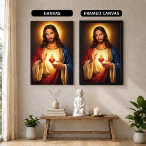 May include: Two wall art displays labeled CANVAS and FRAMED CANVAS featuring a portrait of Jesus Christ with a glowing Sacred Heart. The figure wears a red and blue robe over a cream garment, with a golden halo radiating light behind the head.