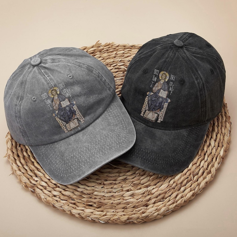 Set of two vintage-inspired washed cotton caps in gray and black, each adorned with a detailed embroidery of Christ sitting on a throne. The design exudes a powerful faith-based message, perfect for expressing religious beliefs. These unisex hats offer a comfortable and adjustable fit, ideal for everyday wear, casual gatherings, or church activities. A thoughtful gift for believers or anyone seeking stylish, meaningful accessories.