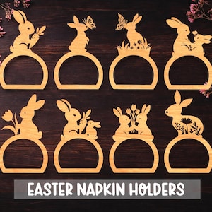 Op de afbeelding: Houten paasservetringen met silhouetten van konijnen in verschillende ontwerpen, waaronder konijnen met wortels, vlinders en bloemen. De ringen zijn gerangschikt op een donker houten oppervlak, met de tekst "EASTER NAPKIN HOLDERS".
