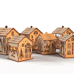 Peut inclure: Ensemble de six photophores en forme de maison en bois. Chaque maison pr&eacute;sente des motifs d&eacute;coup&eacute;s de sapins, de cerfs et d'&eacute;toiles. Les toits sont perc&eacute;s de trous en forme d'&eacute;toiles, et chacun a une petite boucle.