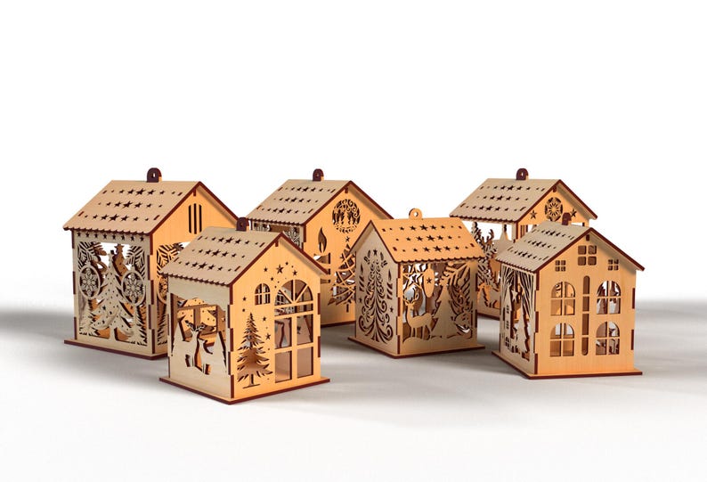 Peut inclure: Ensemble de six photophores en forme de maison en bois. Chaque maison pr&eacute;sente des motifs d&eacute;coup&eacute;s de sapins, de cerfs et d'&eacute;toiles. Les toits sont perc&eacute;s de trous en forme d'&eacute;toiles, et chacun a une petite boucle.