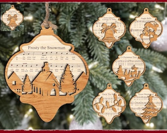 Peut inclure: Ornements de Noël en bois avec divers motifs, dont une scène d'église avec le texte "Frosty the Snowman" et des notes de musique. D'autres ornements présentent une cloche, le Père Noël, un sapin de Noël et les textes "Santa Claus Is Coming To Town", "Jingle Bells", "O Christmas Tree", "Deck The H", et "Winter Wonderland".