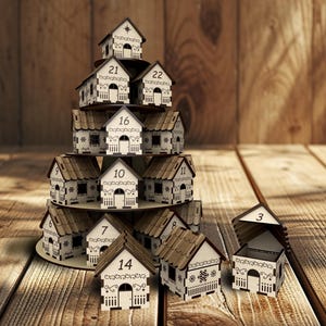 May include: A wooden advent calendar shaped like a Christmas tree, featuring small house-shaped boxes with numbers 3, 7, 9, 10, 11, 14, 16, 21, and 22. The houses have white walls, brown roofs, and decorative cutouts.