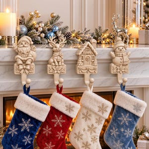 May include: Four cream-colored resin stocking holders featuring a Santa Claus, a reindeer, a house, and a snowman, each with a hook holding a velvet stocking. The stockings are blue, red, cream, and blue, all decorated with white embroidered snowflakes.