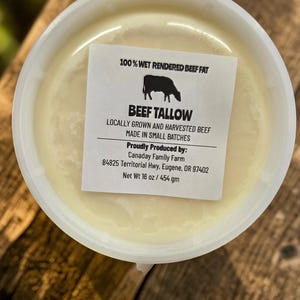 Puede incluir: Un recipiente de plástico blanco lleno de una sustancia cremosa de color amarillo claro, etiquetado como "BEEF TALLOW". La etiqueta también indica "100% WET RENDERED BEEF FAT" y "Net Wt 16 oz / 454 gm."