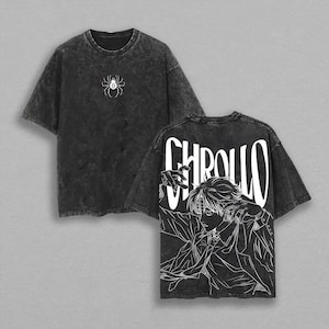 Op de afbeelding: Twee donkergrijze t-shirts. Eén shirt heeft een witte spinnenafbeelding op de voorkant. Het andere shirt heeft het woord "CHROLLO" in het wit op de achterkant, samen met een witte illustratie van een persoon.