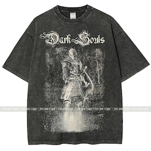 Op de afbeelding: Donkergrijs T-shirt met een verweerde afbeelding van een ridder met zwaard en schild, met de tekst "Dark Souls". Het shirt heeft een vintage, versleten uitstraling.