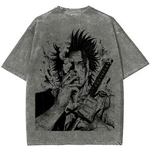 May include: Gray acid wash t-shirt featuring a black graphic of a person smoking a cigarette and holding a sword. The graphic is a detailed illustration with a manga or anime style.