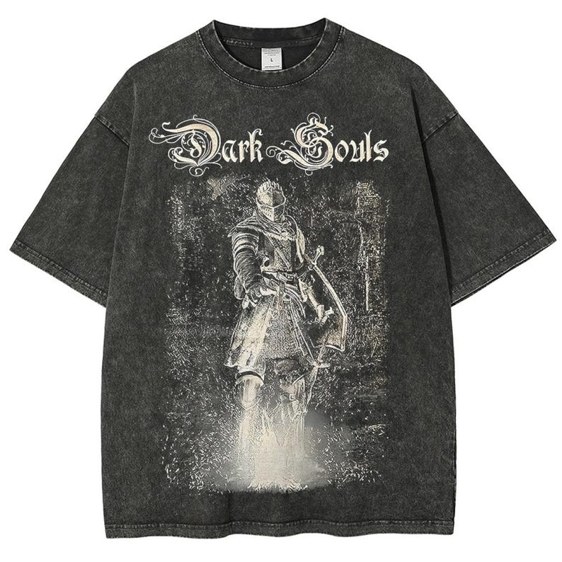 Op de afbeelding: Donkergrijs T-shirt met een verweerde afbeelding van een ridder met zwaard en schild. De tekst "Dark Souls" staat in een sierlijk lettertype boven de ridder gedrukt. Het shirt heeft een vintage, gewassen uitstraling.