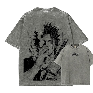 May include: Gray t-shirts with a distressed graphic print. The larger shirt features a detailed black and white illustration of a person with a sword and cigarette. A smaller shirt shows a black bull graphic.