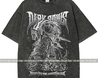May include: Dark grey t-shirt featuring a graphic of a warrior with a sword, the words "DARK SOULS" above, and "ARTORIAS THE ABYSSWALKER" below. The shirt has a vintage, washed appearance.
