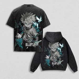 Op de afbeelding: Zwart t-shirt en hoodie set met een afbeelding van een anime-personage met stekelig haar en turquoise accenten. Het woord "KILLUA" staat eronder gedrukt. De kleding heeft een verweerde, vintage uitstraling.