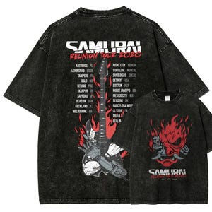 Könnte beinhalten: Schwarze, übergroße T-Shirts mit Used-Look. Auf der Vorderseite befindet sich eine rot-weiße Samurai-Grafik mit Flammen. Auf der Rückseite sind eine Gitarre und eine Liste von Tourstädten, darunter Berlin und Detroit.