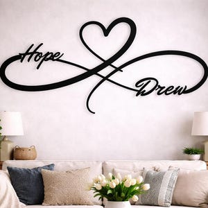Op de afbeelding: Een zwart wandbord met een oneindigheidssymbool verweven met een hartvorm. Het woord Hope is in een cursief handschrift geschreven aan de linkerkant van de oneindigheidslus, en het woord Drew staat in een bijpassend lettertype aan de rechterkant.