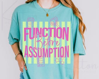 May include: A turquoise t-shirt with the words "FUNCTION Before ASSUMPTION" in pink, set against a background of vertical lime green stripes. The shirt features graphic icons of a coffee cup, magnifying glass, checklist, and stars.