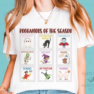 Könnte beinhalten: Ein weißes T-Shirt mit einem Grafikdruck mit dem Titel "BOOHAVIORS OF THE SEASON" und neun quadratischen, briefmarkenartigen Illustrationen. Jede Briefmarke zeigt eine Halloween-Figur mit einem Verhaltensbegriff: sensorischer Geist, Extinktions-Katze, greifbarer Vampir, Verstärkungs-Zombie, Flucht-Hexe, Mand-Geist, echoischer Papagei, Aufmerksamkeits-Monster und Paarungs-Geister.