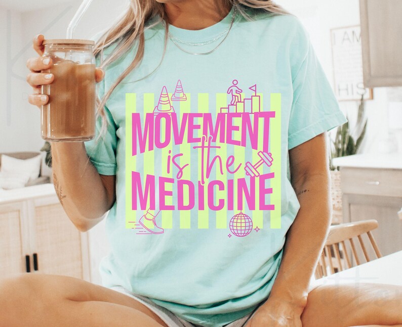 May include: A light blue t-shirt with the text "MOVEMENT is the MEDICINE" in pink and yellow. The graphic includes images of a person climbing stairs, a dumbbell, a disco ball, and a running shoe.