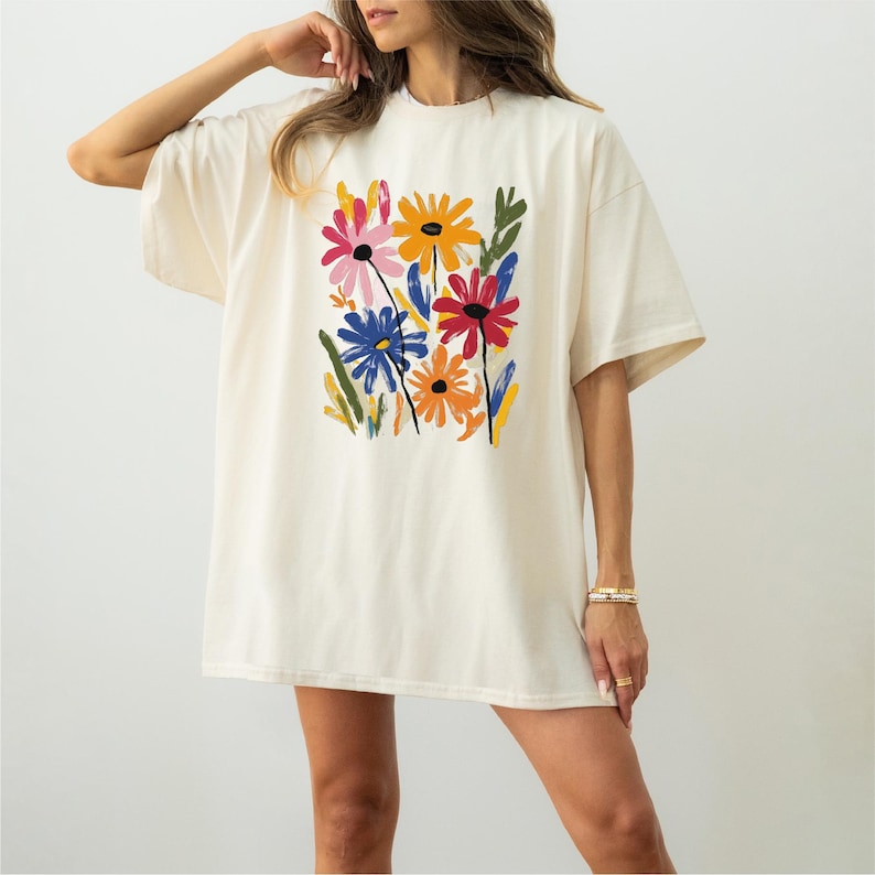 A woman wearing a white t-shirt with a colorful floral design.