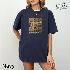 A navy blue t-shirt with a graphic design featuring a collage of nine different portraits arranged in a 3x3 grid.