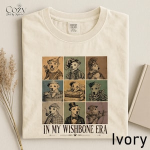 A white t-shirt with a collage of nine illustrations of dogs in various poses and outfits, along with the text "IN MY WISHBONE ERA" printed on it.