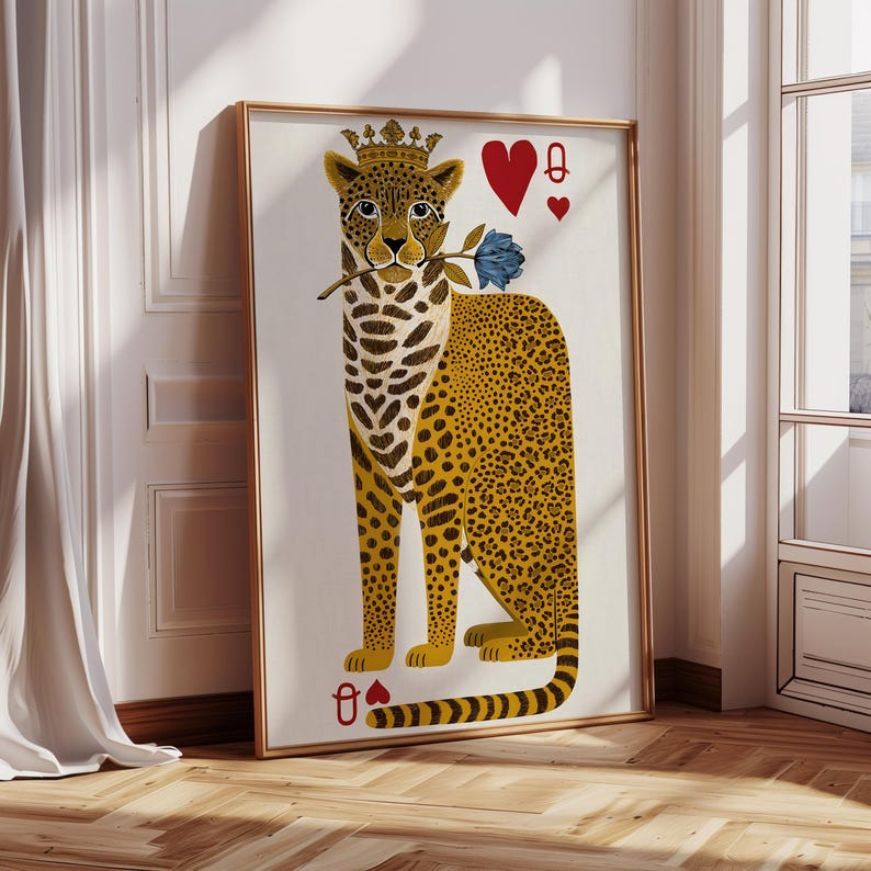 May include: A framed art print featuring a stylized leopard wearing a crown and holding a blue rose. The leopard is depicted as the Queen of Hearts playing card, with red heart symbols in the upper right and lower left corners. The leopard has a yellow and brown spotted coat.
