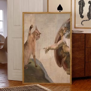 Könnte beinhalten: Ein humorvoller Kunstdruck, der eine Katze zeigt, die die Hand Gottes in einer Nachbildung von Michelangelos berühmtem Gemälde "Die Erschaffung Adams" berührt.