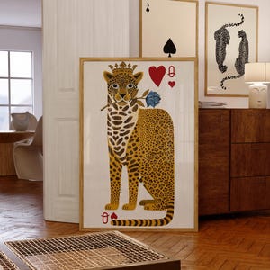May include: A framed art print featuring a leopard wearing a crown and holding a blue rose, with playing card symbols. The leopard has a yellow and brown spotted coat. Additional framed art pieces are visible in the background.