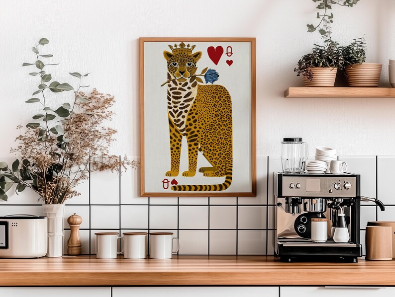 May include: A framed art print featuring a leopard wearing a crown and holding a blue rose. The leopard is depicted as the Queen of Hearts playing card. The print has a wooden frame and is displayed in a kitchen setting.