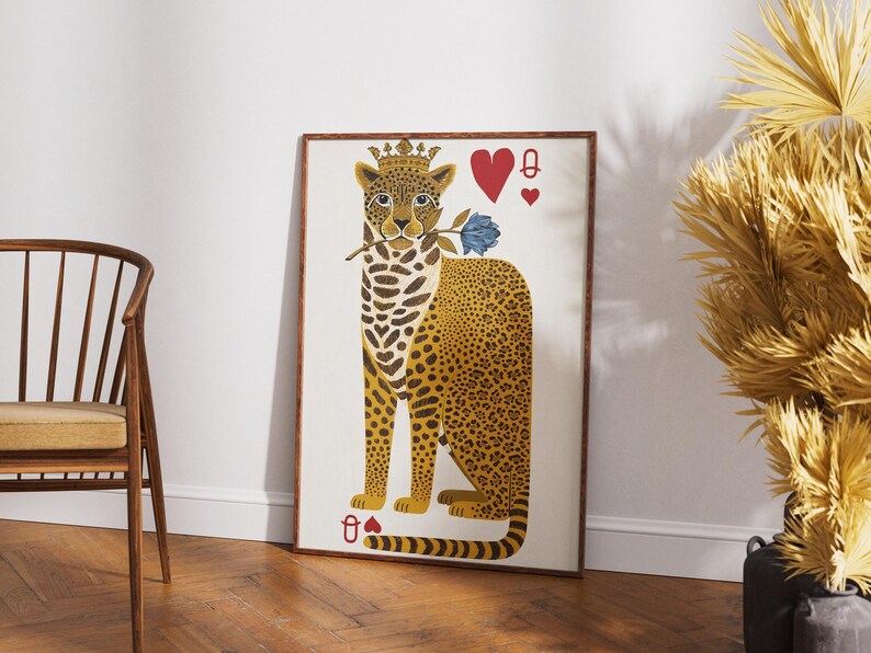 May include: A framed art print featuring a stylized leopard wearing a crown and holding a blue rose. The leopard has a yellow and brown spotted coat. The artwork includes playing card symbols: a red heart and a spade.