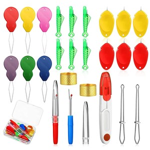 May include: A sewing tool kit containing colorful plastic needle threaders, green fish-shaped threaders, yellow and red oval threaders, two gold-toned metal thimbles, seam rippers with protective caps, and two wire loop tools, all stored in a clear box.