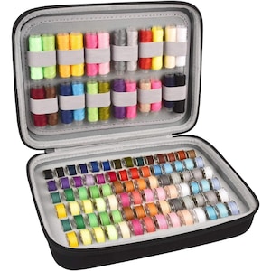 May include: A black zippered carrying case containing a collection of sewing supplies. The top section holds rows of vertical thread spools in various colors, while the bottom section contains numerous small, circular bobbins in a wide array of hues.