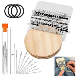 May include: A darning loom kit featuring a metal weaving tool with silver hooks, a round wooden disc, three black elastic bands, a clear plastic tube containing multiple sewing needles, and several individual metal needles of varying lengths.