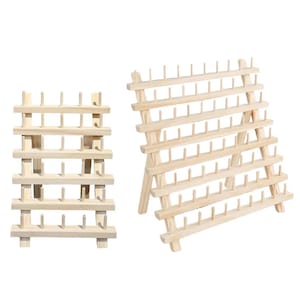 May include: Two light-colored wooden thread racks with multiple horizontal shelves and vertical pegs for organizing spools. The racks feature a tiered, angled design with a sturdy frame, providing a clear view of the natural wood grain texture.