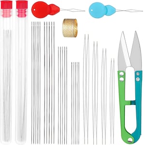 May include: A sewing kit containing two clear plastic tubes with red caps filled with needles, a gold-toned metal thimble with a textured surface, two plastic needle threaders in red and blue, various long metal needles, and green and blue thread snips.