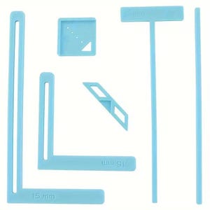 May include: A set of light blue plastic sewing and quilting templates including two L-shaped rulers with 15 mm markings, a T-shaped ruler, a square guide with four small holes, a diagonal strip guide, and a long straight edge ruler for fabric.