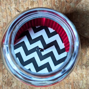 May include: A silver jar with a black and white chevron pattern and a red velvet lining inside.
