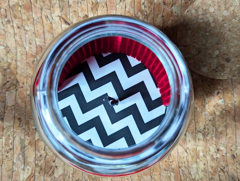May include: A silver jar with a black and white chevron pattern and a red velvet lining inside.