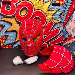 May include: A white ceramic mug with a black handle and the text "But First, Coffee" in a bold, black font. The mug is filled with a dark liquid, likely coffee, and sits on a light-colored surface.